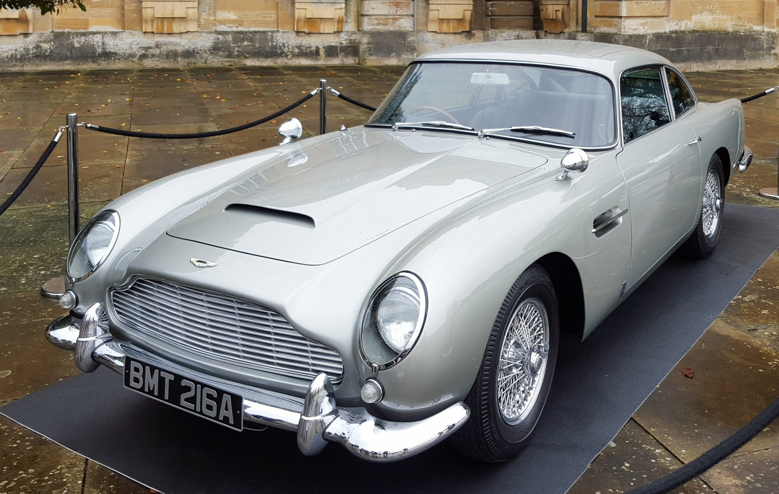 1964 Aston Martin DB5 in silver parked outside a grand hotel, chrome wire wheels