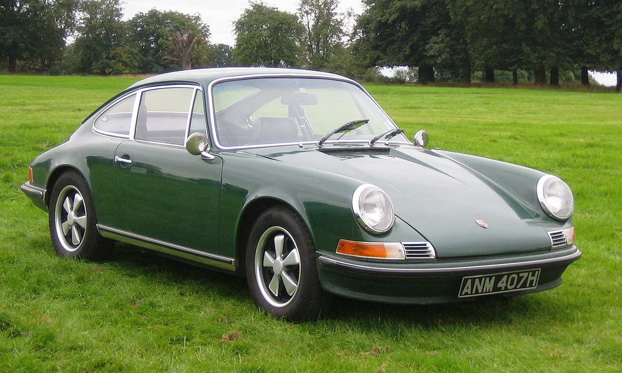 1964 Porsche 911 in light ivory, rear-engine silhouette on a mountain pass
