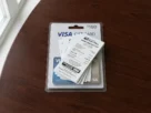 Paper money order receipts stacked on top of visa gift card packaging on a wooden table